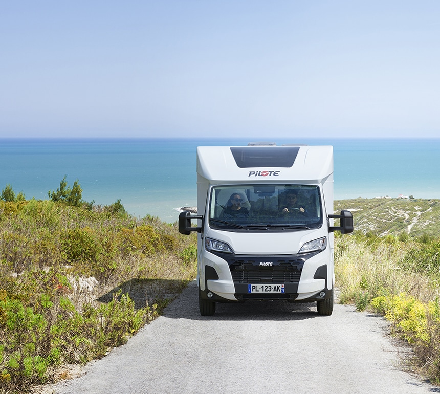 Camping-car profilé Pilote sur une route de Loire Atlantique bordée de verdures, s'éloignant de la mer.